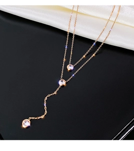 Dettaglio della collana a doppio strato in titanio oro rosa con tre zirconi brillanti