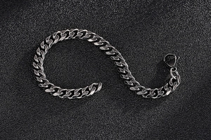 Macro detail of silver Cuban link bracelet with lobster clasp on black leather