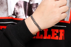Close-up of a vintage black stainless steel Cuban chain bracelet on a male wrist