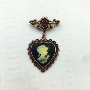 Vintage Victorian style cameo brooch featuring a heart pendant and bronze filigree detail