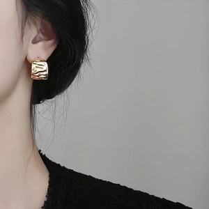 Golden chunky waterdrop hoop earrings with textured finish worn by a model