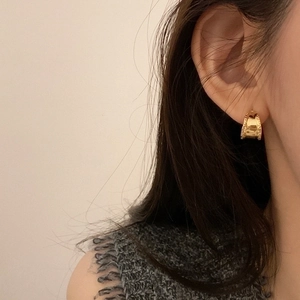 Irregular wide gold hoop earrings with hammered texture worn by model for elegant style