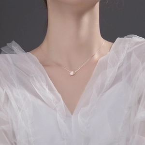 Close-up of rose gold heart pendant with pavé diamonds on a model with white lace