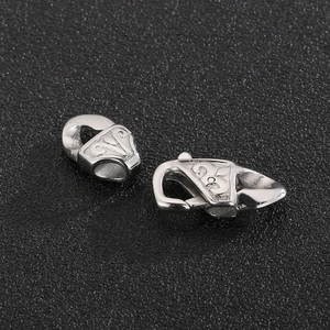 Detail shot of two silver metal jewelry clasps with embossed patterns on black background