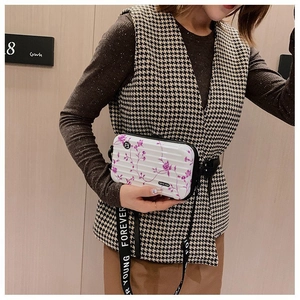Mini suitcase-style crossbody bag with purple floral patterns and a wide graphic strap