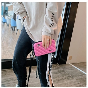 Detail of pink hardshell mini suitcase crossbody bag with Forever Young strap