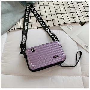 Macro shot of purple hardshell mini suitcase bag with Forever Young printed strap