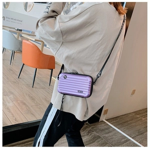 Detail of purple mini suitcase crossbody bag with stylish patterned woven shoulder strap
