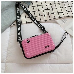 Close-up of pink hardshell mini suitcase bag with wide lettered strap and glossy finish
