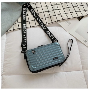 Detail of light blue mini suitcase bag with rigid hardshell and striped texture