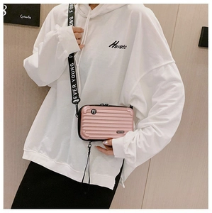 Detail of pink hardshell mini suitcase bag with wide branded shoulder strap