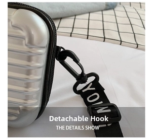 Detail showing the detachable black hook and branded wide strap on the silver mini case bag