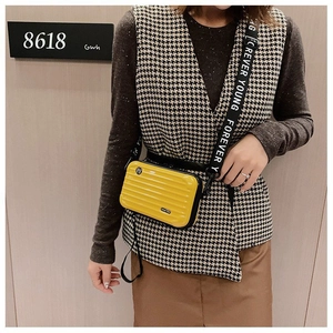 Close-up of yellow hardshell mini suitcase bag with Forever Young printed strap