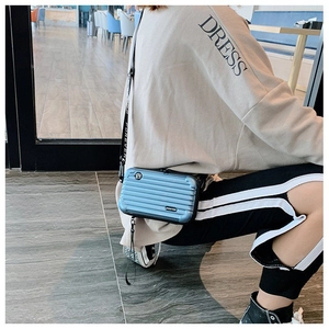 Blue miniature suitcase crossbody bag with vertical stripe design and wide logo strap