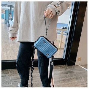 Close-up of blue hardshell mini suitcase bag with vertical grooves and logo strap