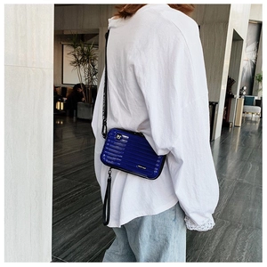 Mini royal blue hard shell trunk bag with wide logo strap shown on a model