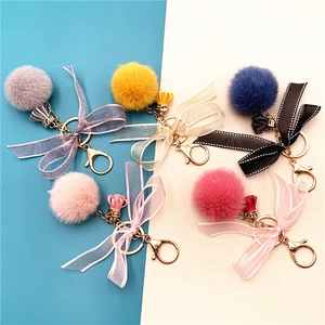 Flat lay of colorful plush faux fur keychains with lace bows and tassels in five colors