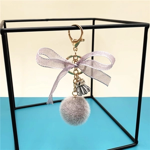 Detail of gray plush ball keychain with lavender lace bow and silver tassel accessory