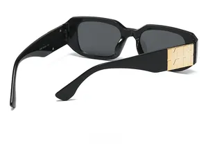 Vue détaillée de lunettes de soleil noires avec charnières dorées et logo en relief