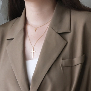 Dettaglio della collana a doppio strato con croce dorata indossata da una modella