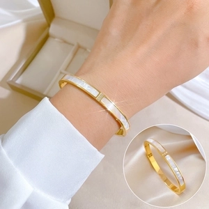 Gold plated stainless steel open bangle with white shell inlay and crystal detail