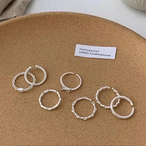 Set of 6 silver minimalist open rings with twist and chain designs on a cork tray