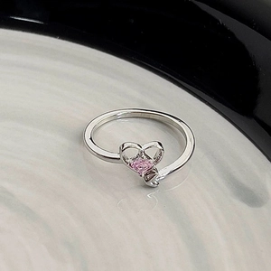 Macro shot of silver ring with pink heart-shaped zircon and hollow heart-shaped design