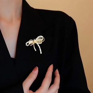 Elegant gold bow brooch with micro-pave zircons and pearls on a black blazer lapel