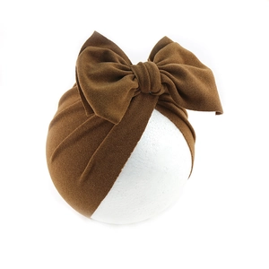 Detail view of a brown velvet turban hat with a large bow for toddlers and infants