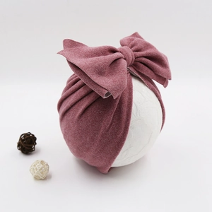 Detail of baby turban hat in dusty pink cashmere-like fabric with large bow detail