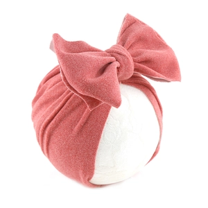 Detail of baby turban hat in dusty rose with a large decorative bow on a model head