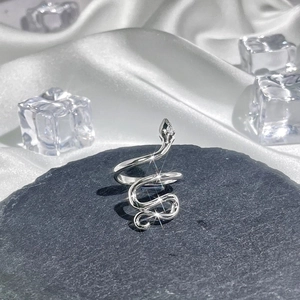 Macro shot of silver snake-shaped ring on gray stone with silk and ice cubes