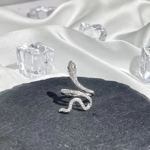 Detail of silver snake ring with pavé diamonds and green gemstone eyes on stone