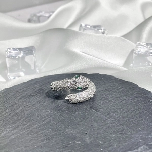 Detail of silver snake ring with green gem eyes and sparkling crystals on stone