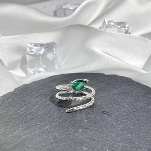 Detailed macro of a silver snake ring with green pear-shaped gemstone and scale texture