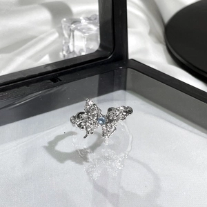 Detailed view of butterfly ring with blue gemstone on white silk in black jewelry box