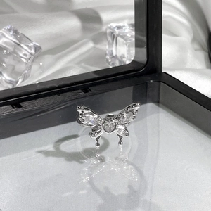 Detailed close-up of silver butterfly ring with clear gems on reflective display surface