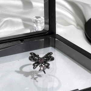 Detailed close-up of a black butterfly ring with pink heart gemstone in a gift box
