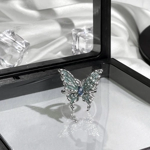 Detail of butterfly ring with blue enamel wings and gemstone on silk background