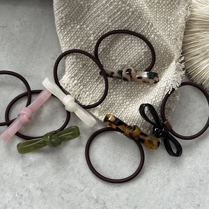 Set of 6 colorful acetate bow hair ties on textured fabric, high ponytail accessories