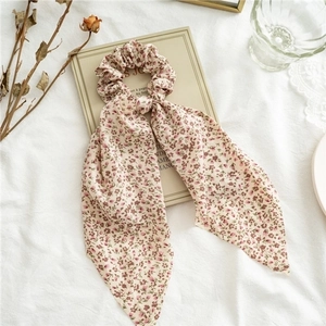 Detailed shot of a floral print hair scrunchie with long ribbons on a vintage book