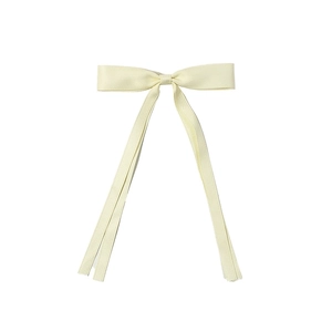 Close-up of light yellow ribbon bow hair clip with long tails on a white background