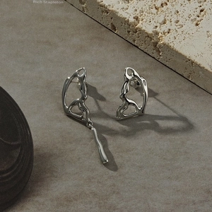 Modern asymmetric silver bow earrings with polished finish and dangling accent charm
