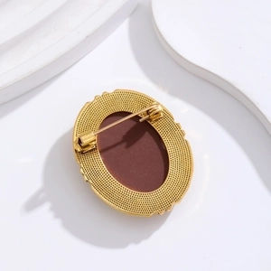 Back view of vintage golden alloy oval brooch with red-brown inlay and safety pin