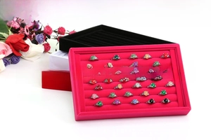 Velvet jewelry display tray with multiple slots holding colorful gemstone rings