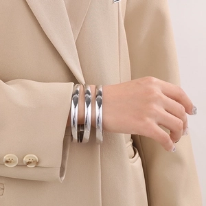 Close-up of three polished silver stainless steel minimalist bangles on a model wrist
