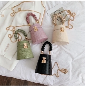 Four elegant mini bucket bags in black, white, purple, and green with faux crocodile texture