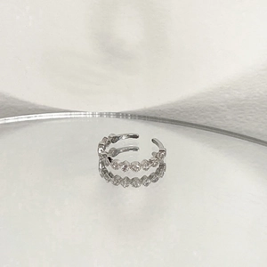 Detail of silver open ring with continuous cubic zirconia inlay on reflective mirror surface