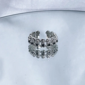 Close-up of irregular textured silver open ring with chain link design on a reflective surface