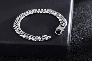 Close-up of silver titanium steel curb chain bracelet with textured dark background